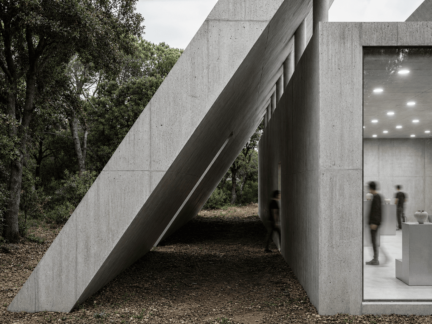 MASS — the workshop pavilion's tilted concrete wing beside the lit gallery window, seen from the forest floor