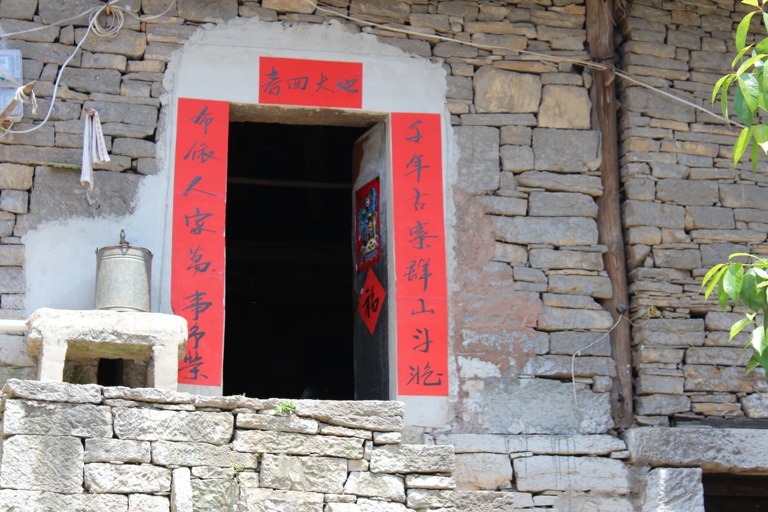A regional slate stone house with a red-papered doorway.