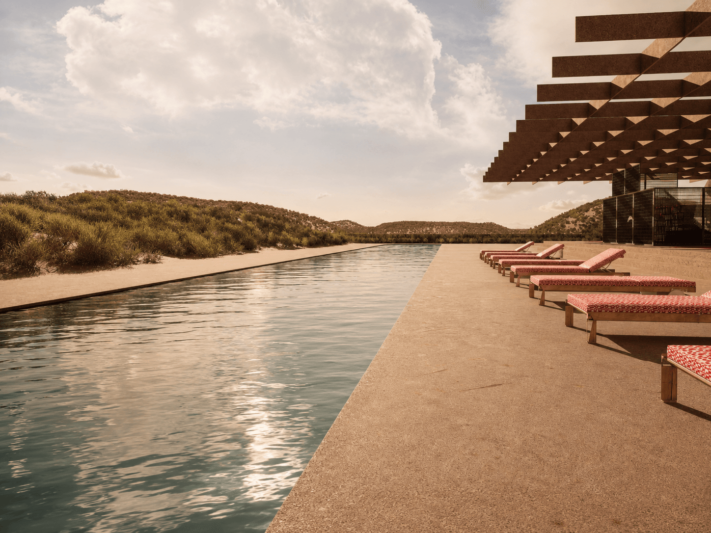 Red loungers along the pool edge in soft afternoon light.