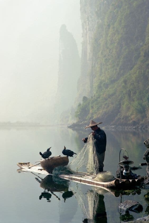 A boatman on still water in low mist.