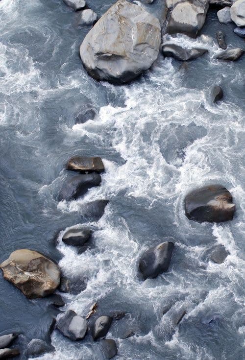 Water running fast over pale river stones.