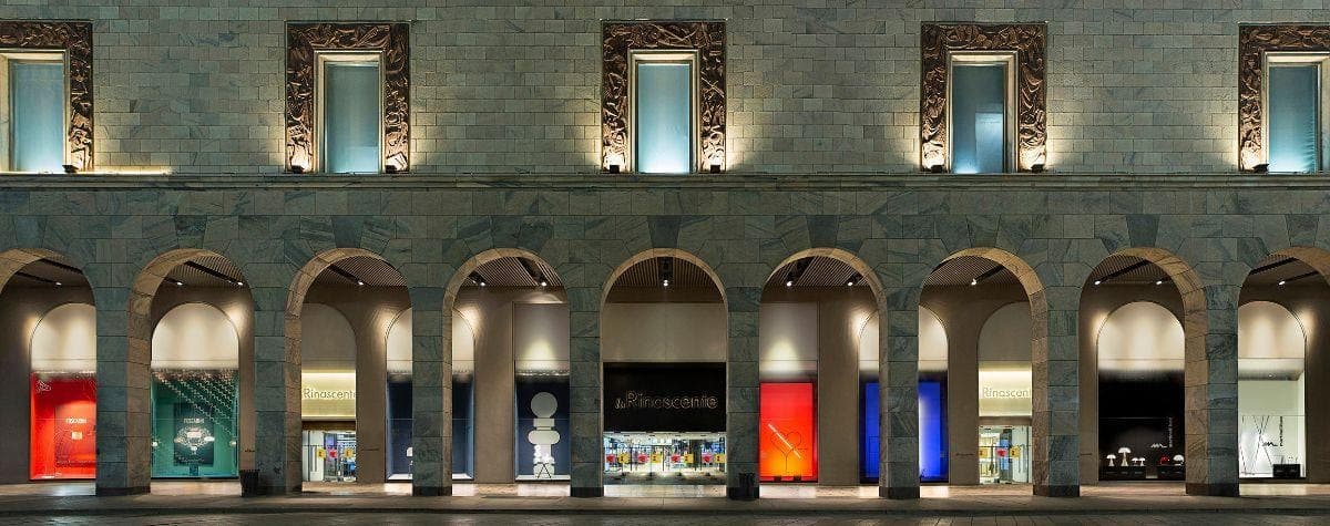 The Rinascente arcade at night, its lit shopfronts running the length of the colonnade.