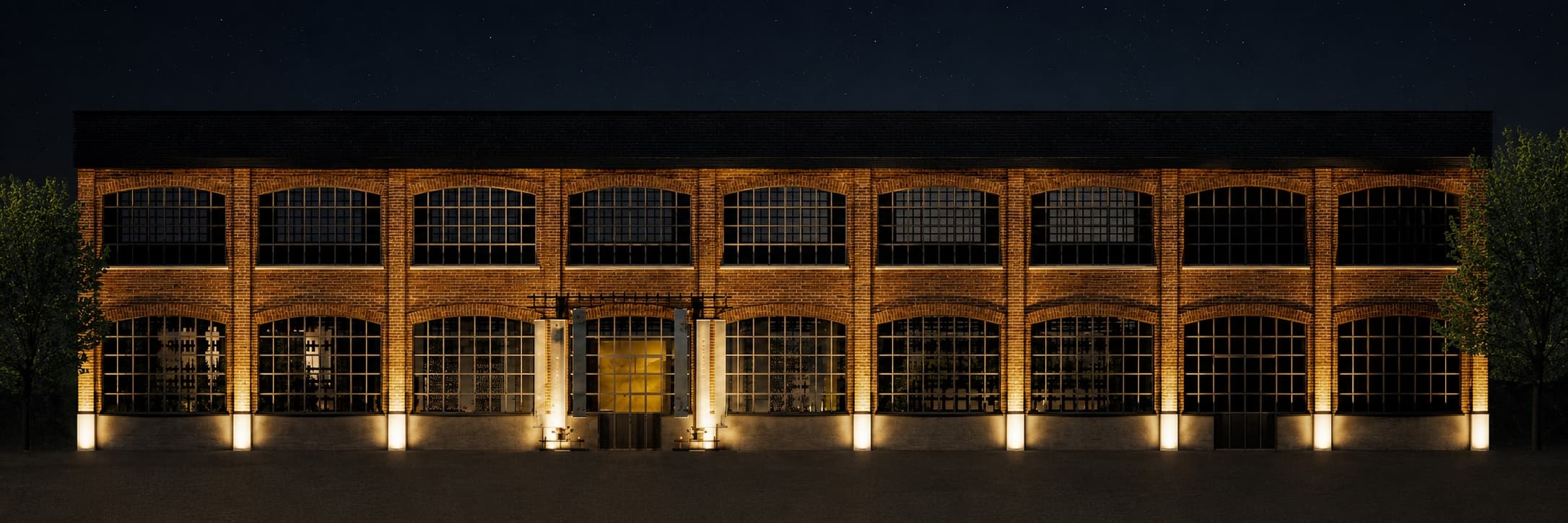 The factory frontage at night, each bay lit from within.