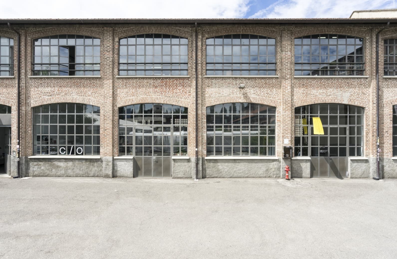 The brick facade of Fabbrica del Vapore, its tall arched industrial windows in a long repeating bay.